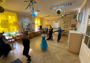 Dzieci w udekorowanej sali tańczą w strojach